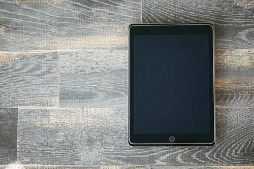 木目の床に置いた大きさが異なるタブレットを重ねる