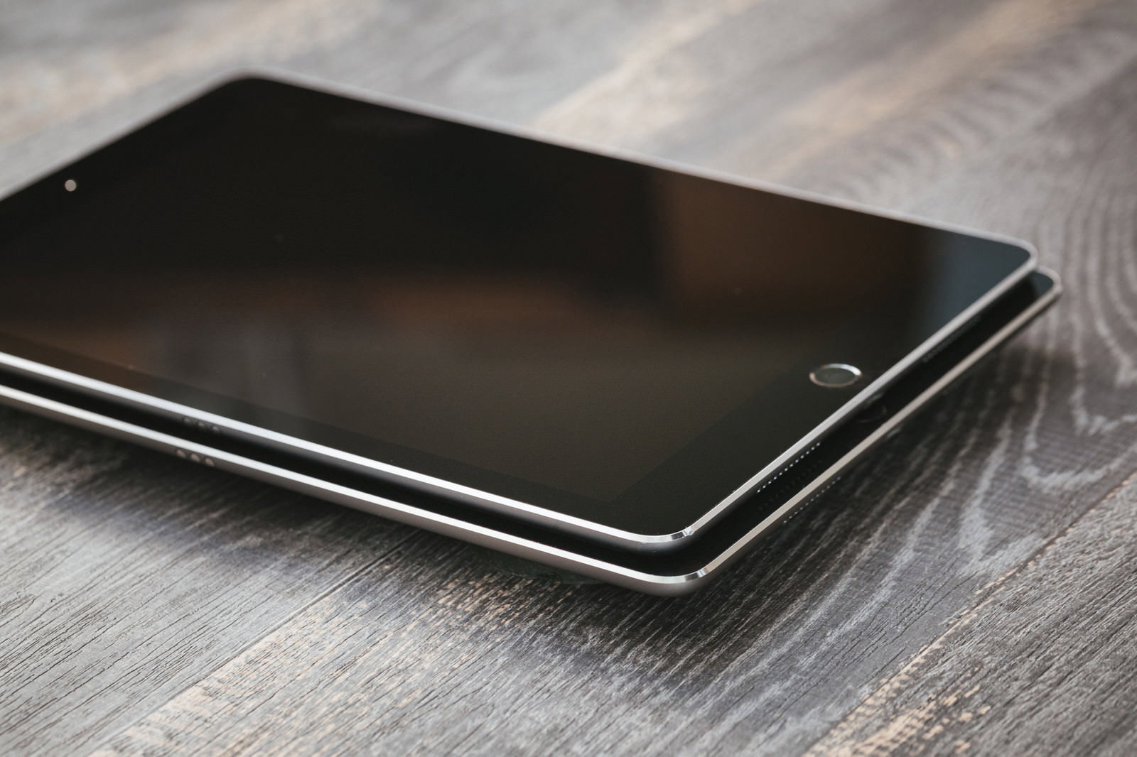 木目調のデスクの上に置かれた黒い画面のタブレット端末