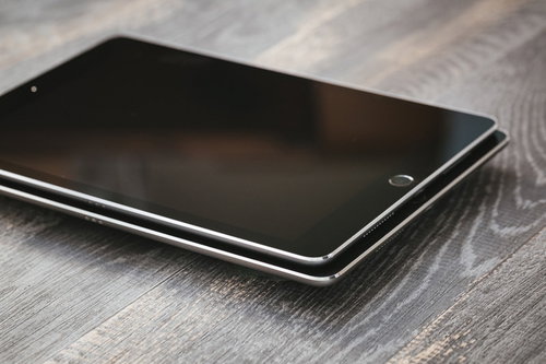 木目調のデスクに重ねて置かれた複数のタブレット端末