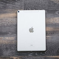 木目のテーブルに置かれたシルバーのタブレット（iPad）の写真