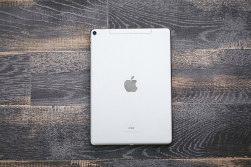 木目のテーブルに置かれたシルバーのタブレット（iPad）