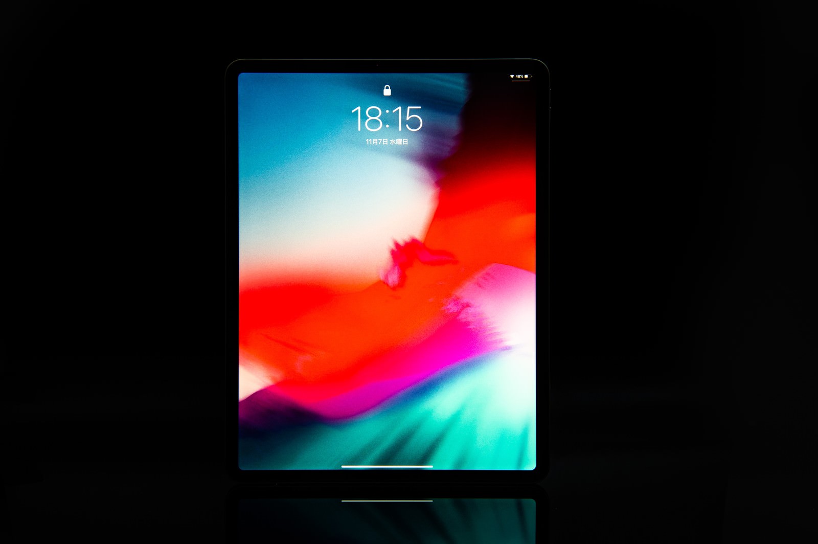 黒背景に置かれた12.9インチiPad Pro 2018、カラフルなグラデーション壁紙を表示