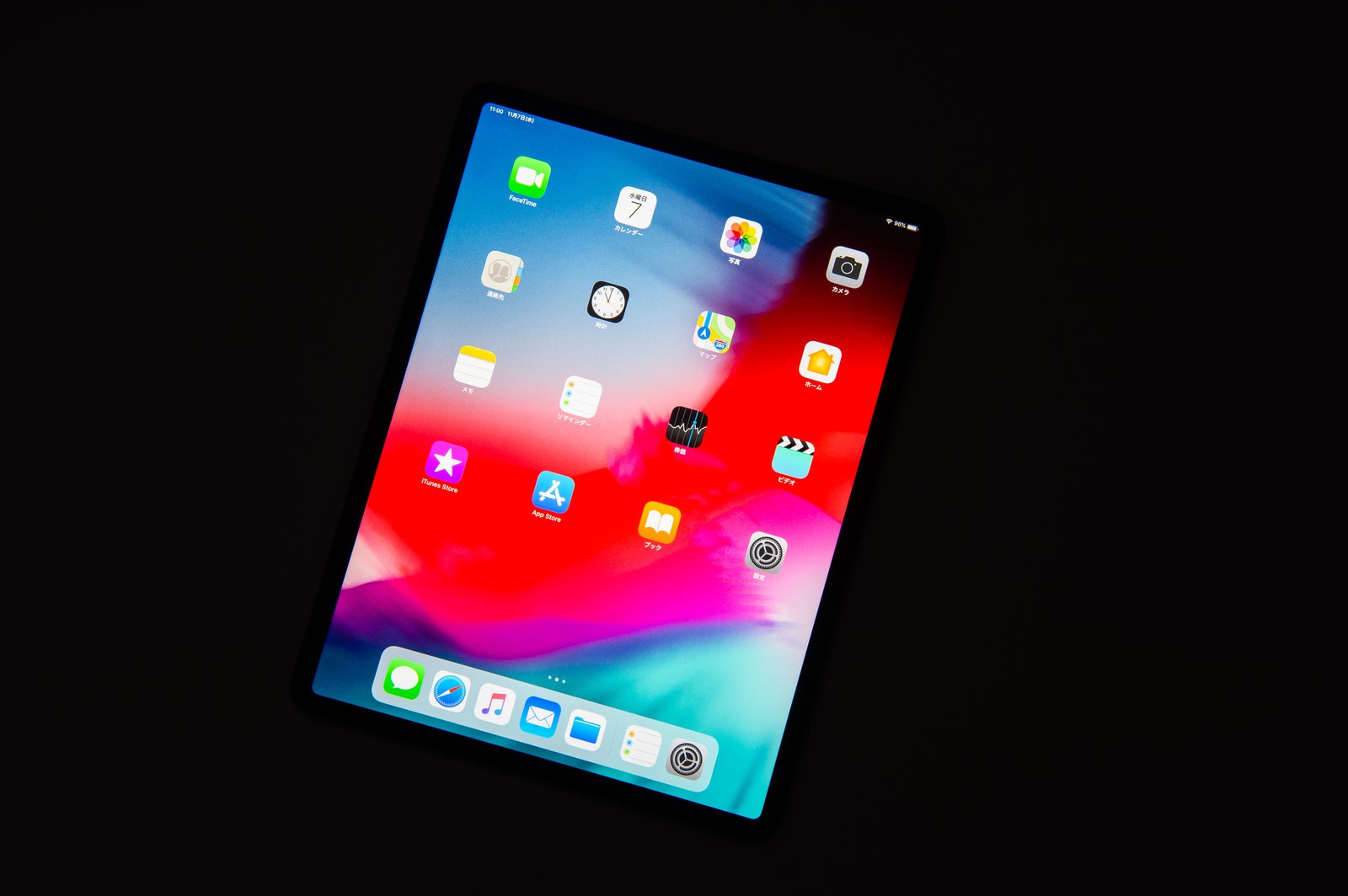 黒い背景に傾けて置かれたタブレットの画面にカラフルなアプリアイコンが表示されている