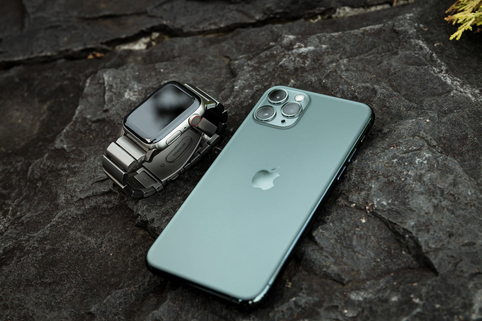 石の上に並んで置かれたチタンApple WatchとiPhone 11 Pro