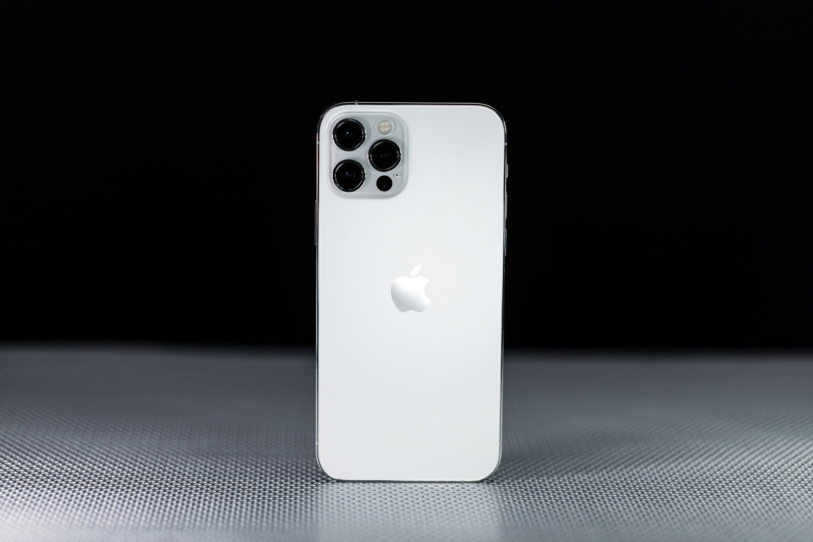 黒い背景に立てかけられた白いiPhone12
