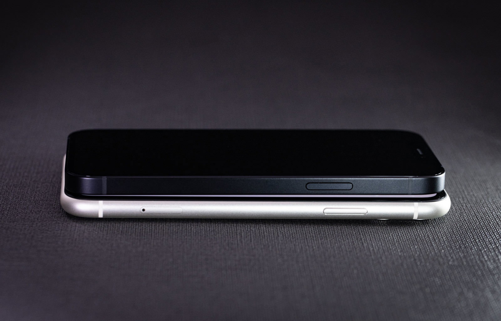 黒い背景の上でiPhone11と12が重ねて配置されたサイズ比較