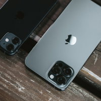 木目のテーブルに並ぶiPhone 12とiPhone 12 Proの写真