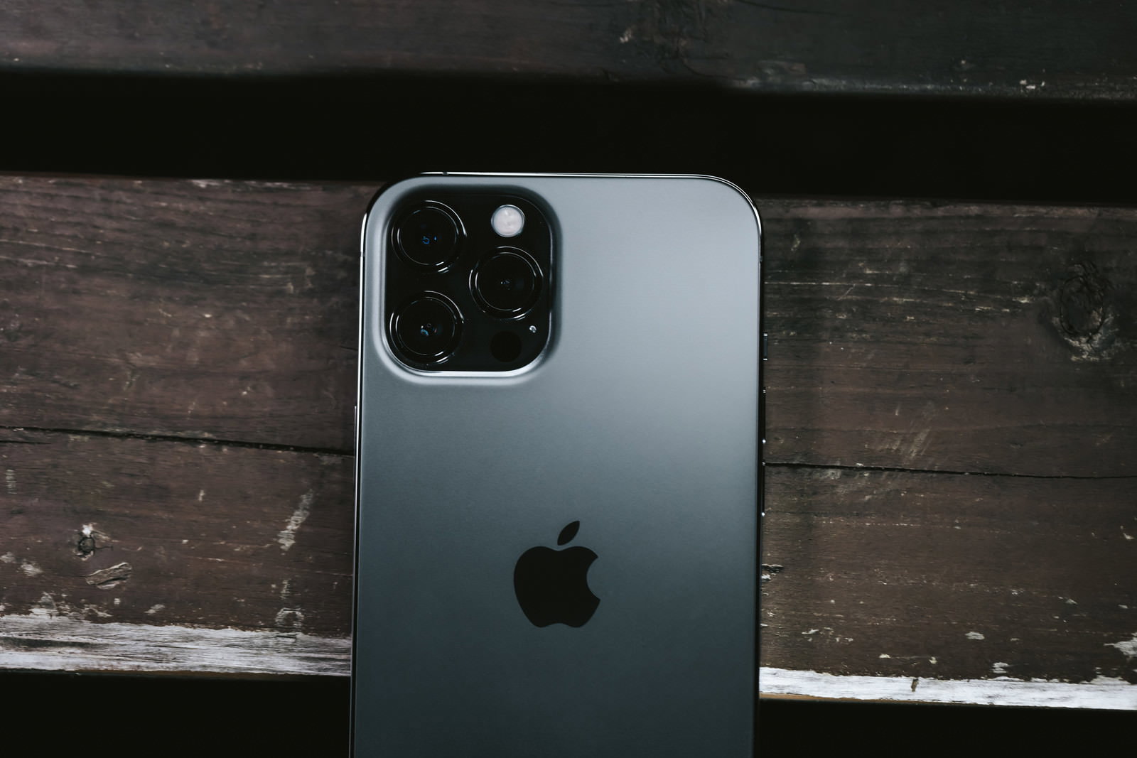 木製テーブルに置かれたiPhone 12 ProのリアカメラとAppleロゴ