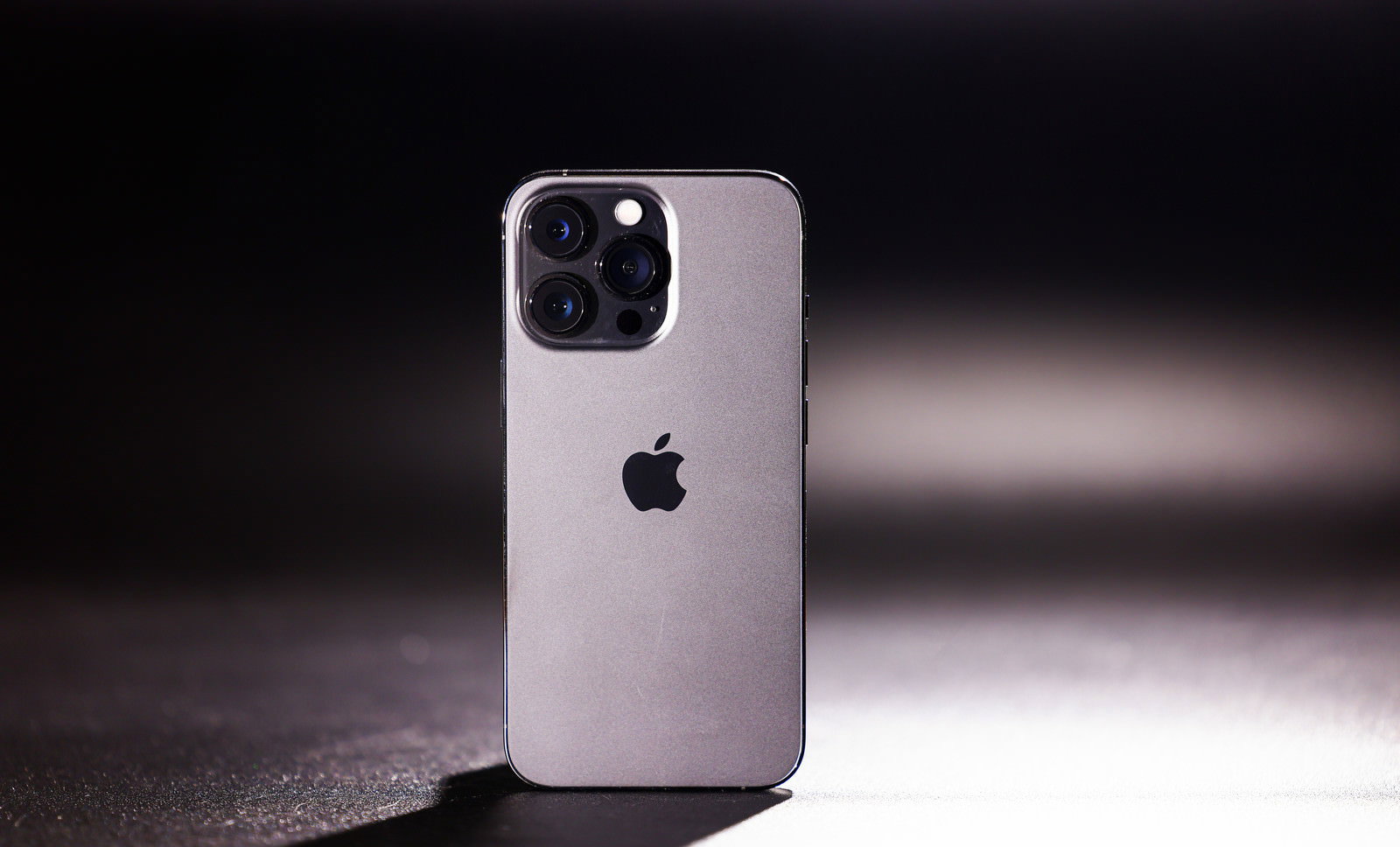 暗い背景に映える直立したシルバーのiPhone 13 Pro