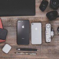 木目のテーブルに置かれたガジェットと最新スマホの写真