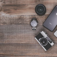 木目調テーブルに並ぶフィルムカメラとiPhone8の写真