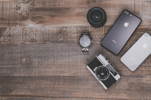 木目調テーブルに並ぶフィルムカメラとiPhone8