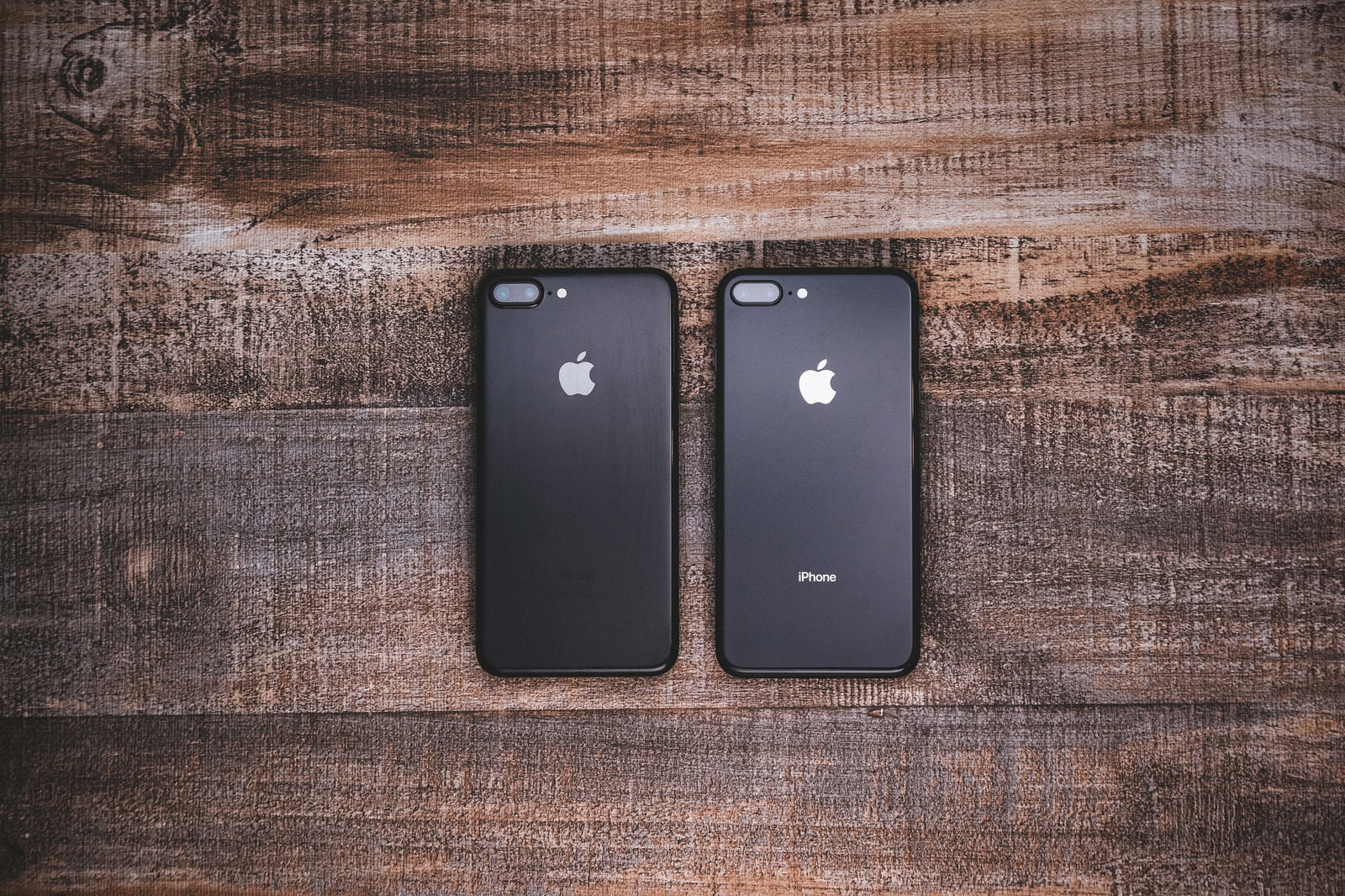 木目テーブルの上に並ぶiPhone 2台の背面