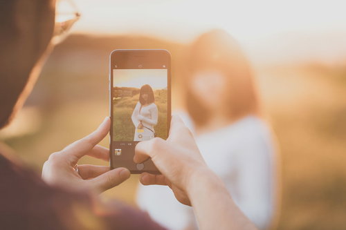 逆光の中iPhoneでグラドルを撮影中のブロガー