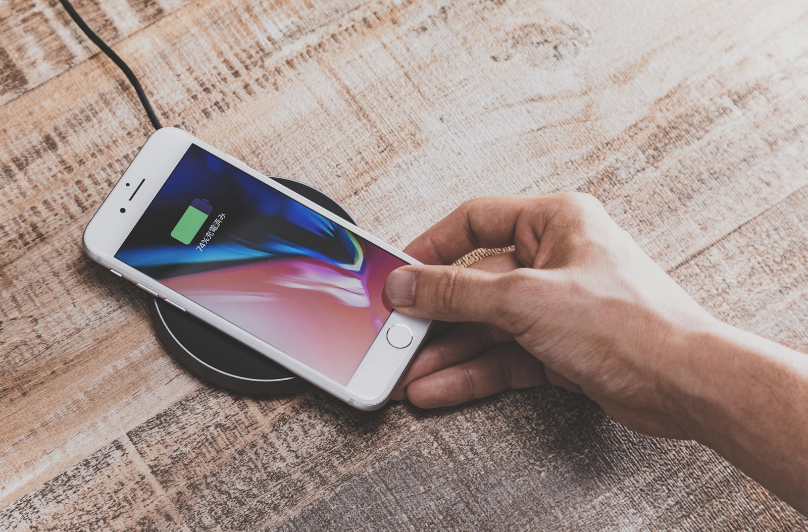 ワイヤレス充電パッドにiPhoneを置く男性の手