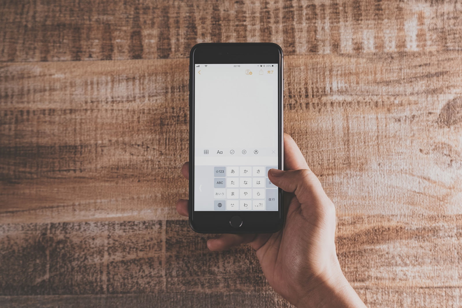 片手でiPhoneを持ち日本語キーボードを操作する手