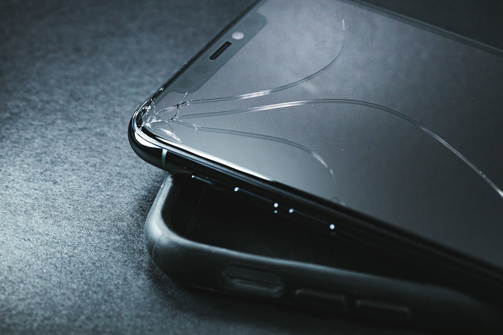 黒い保護ケースを装着したiPhoneの画面に亀裂が入っている