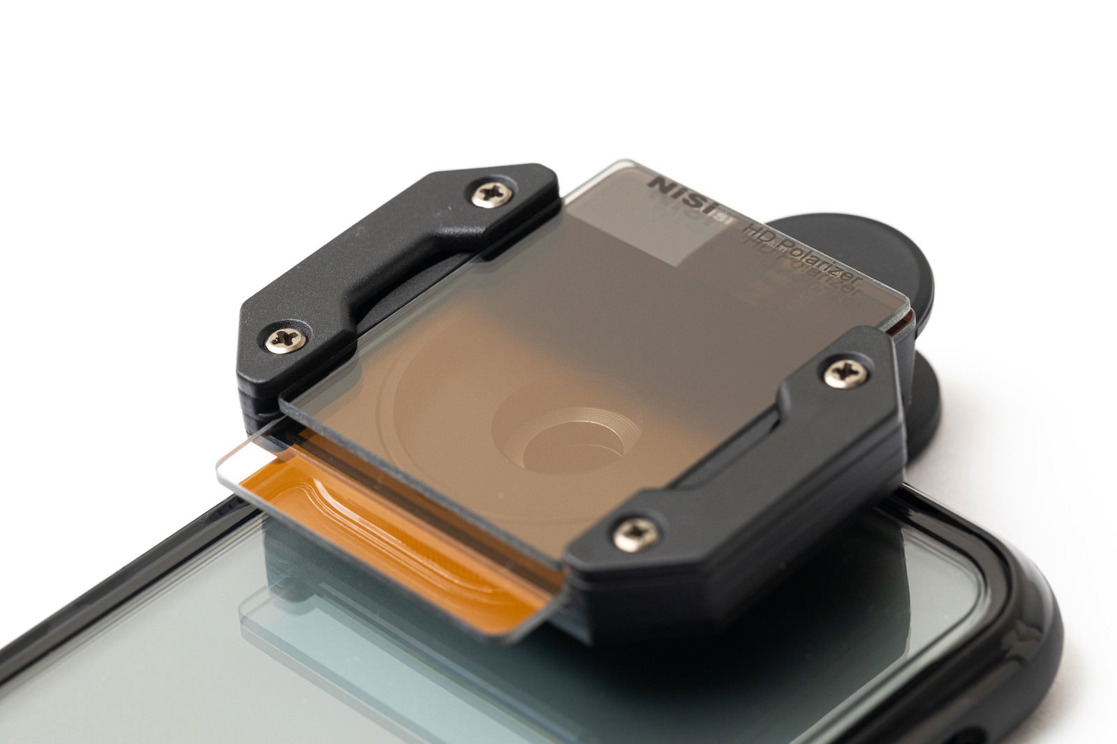 スマートフォンのカメラレンズに装着されたオレンジ色の角型NDフィルター