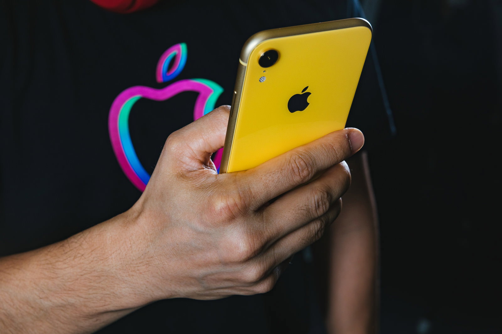 黄色いiPhone XRを両手で持って操作している男性