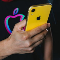 iPhone XR イエローを両手で操作する男性の写真