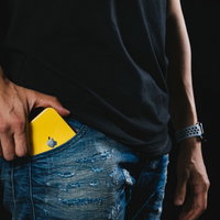 黄色いケースの iPhone XR をジーンズのポケットにしまうの写真