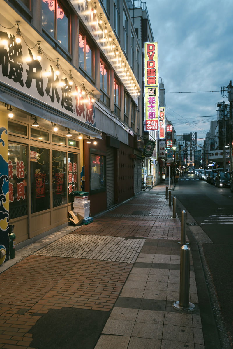 夕暮れ時の伊勢佐木商店街、電飾看板が灯る店舗が並ぶ歩道と車道