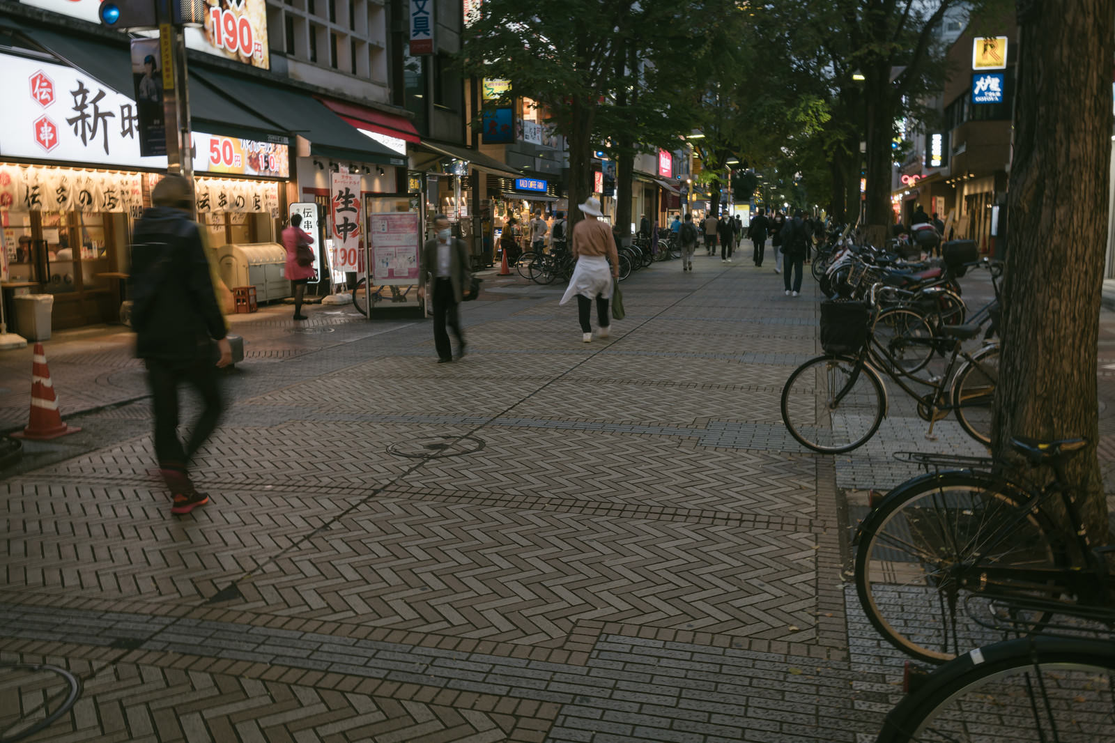 夜のイセザキモールの石畳歩道に停められた自転車と歩く人々