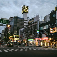 夕暮れ時の伊勢佐木長者町、横断歩道と車道が交差する飲食店街の写真