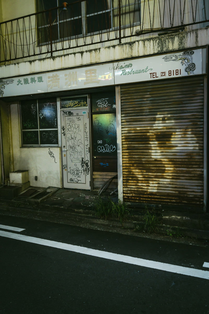シャッターが閉まった店舗の壁面に落書きされた伊勢佐木長者町の空き家