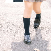 通学する女子高生のローファーとハイソックスの足元の写真