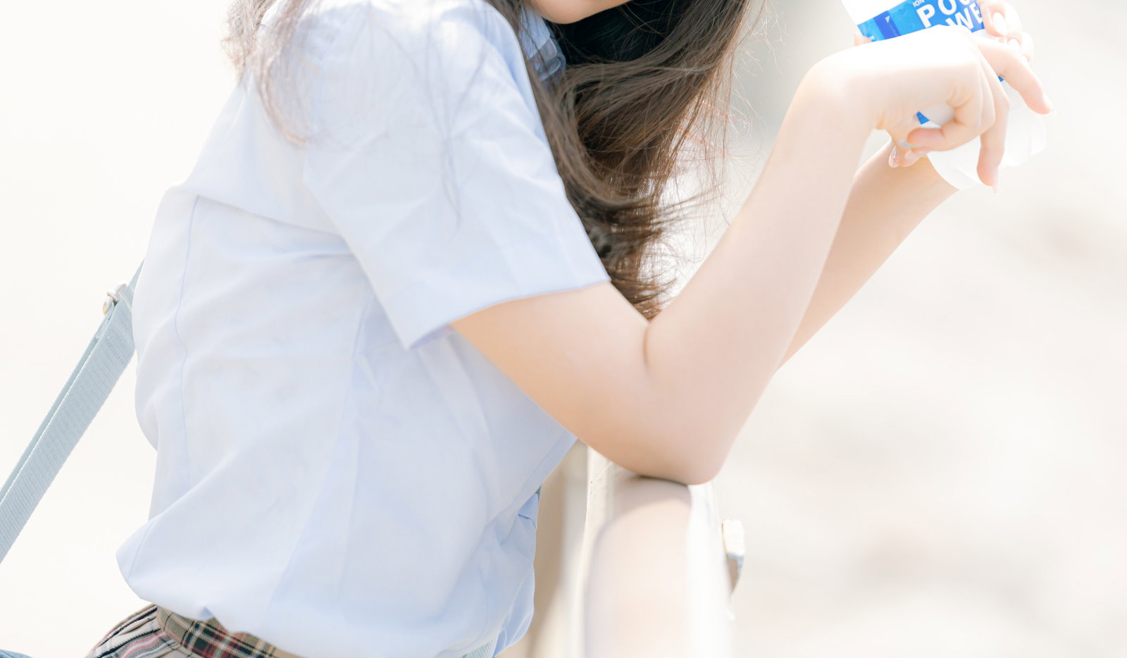 ポカリスエットを手に持って休憩する白シャツ姿の女子高生［モデル：石投げて美奈代］