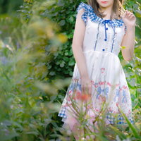 白いワンピースの森ガール風女性が庭の植物に囲まれるの写真