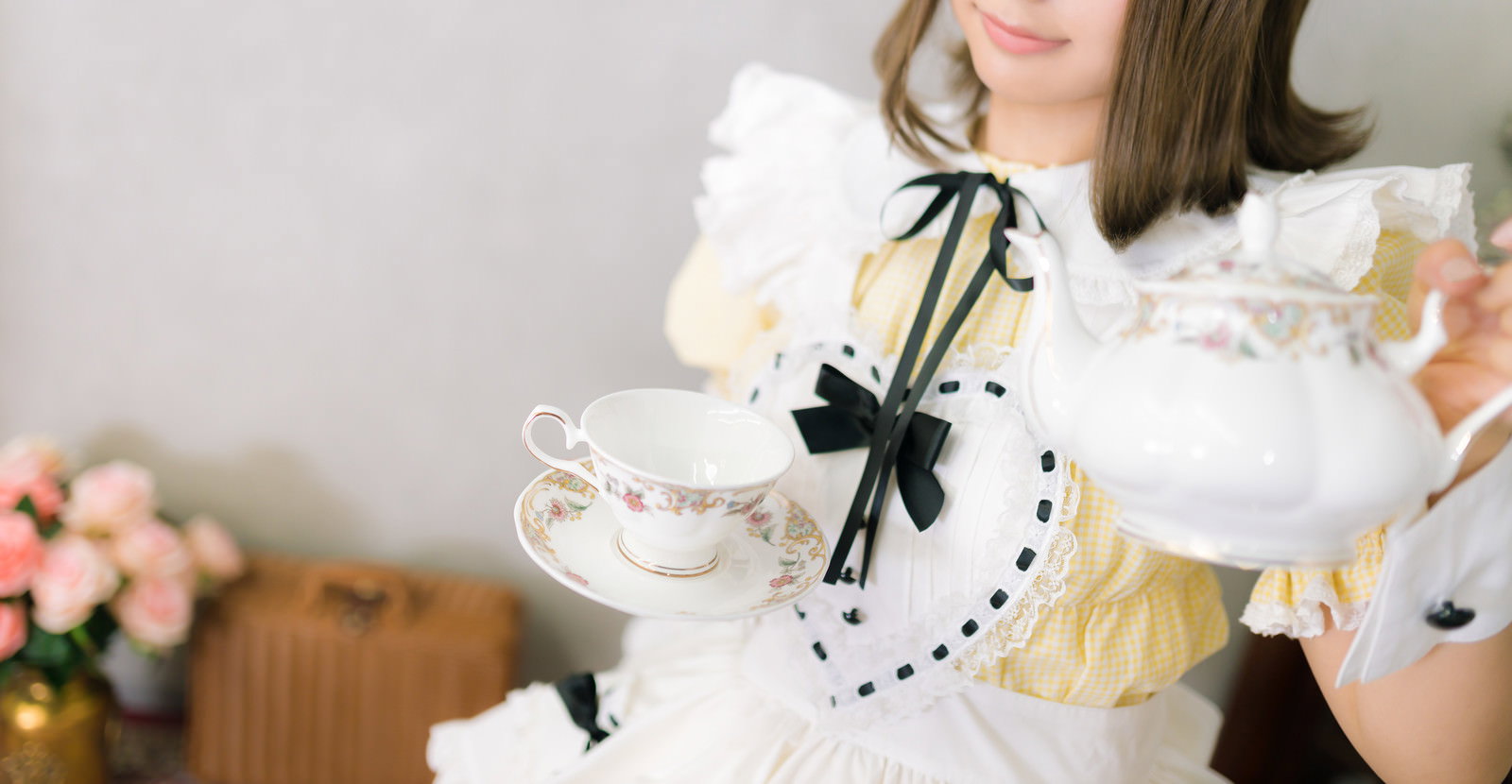 白いメイド服を着た女性が両手でティーカップを持っている［モデル：石投げて美奈代］