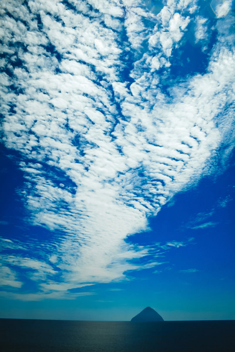青空に規則正しく並ぶ白いふわふわした羊雲の風景