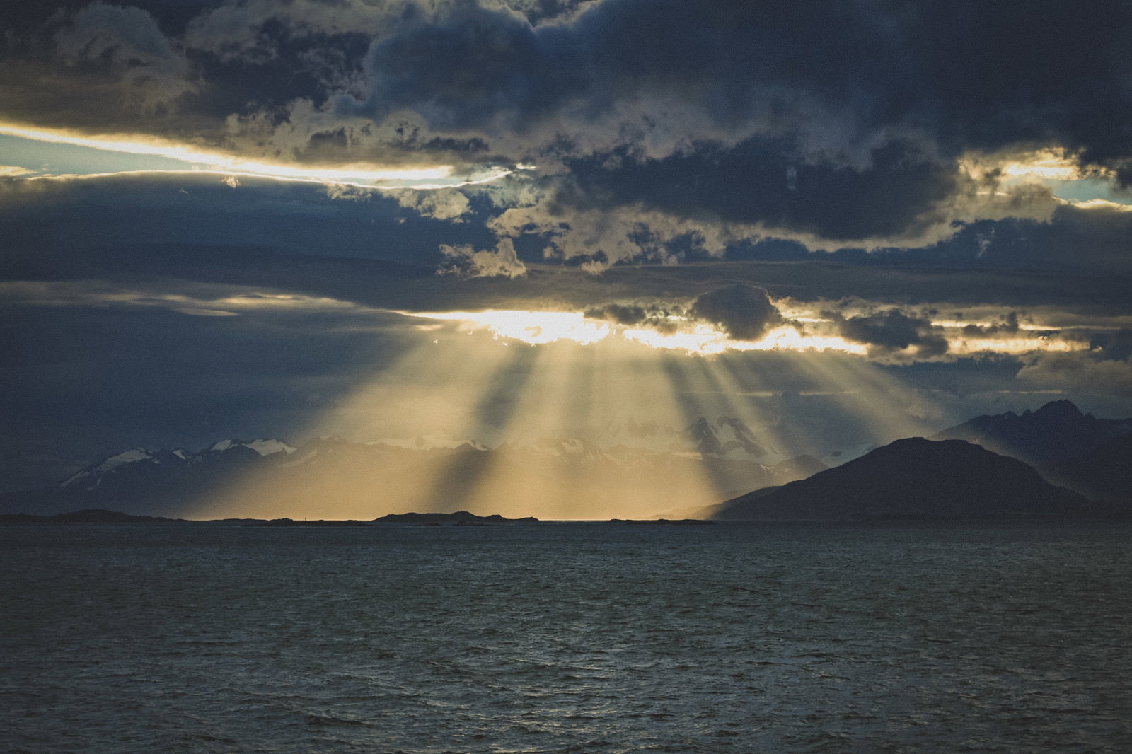 雲間から海と山の景色に向かって放射状に差し込む光芒