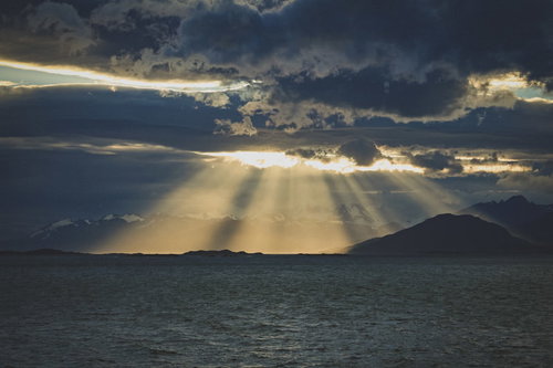 雲間から舞降りる天使のはしご、海と山を照らす光芒