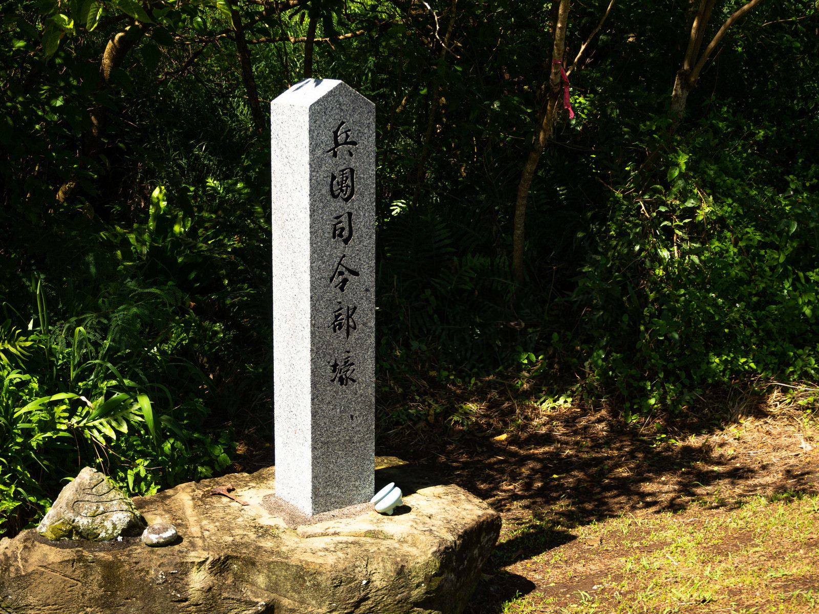 緑の植物に囲まれた白い石の道標、兵団司令部壕と刻まれている