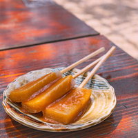 串に刺した蛇の鼻の藤の味噌田楽、こんにゃくの味噌焼きの写真