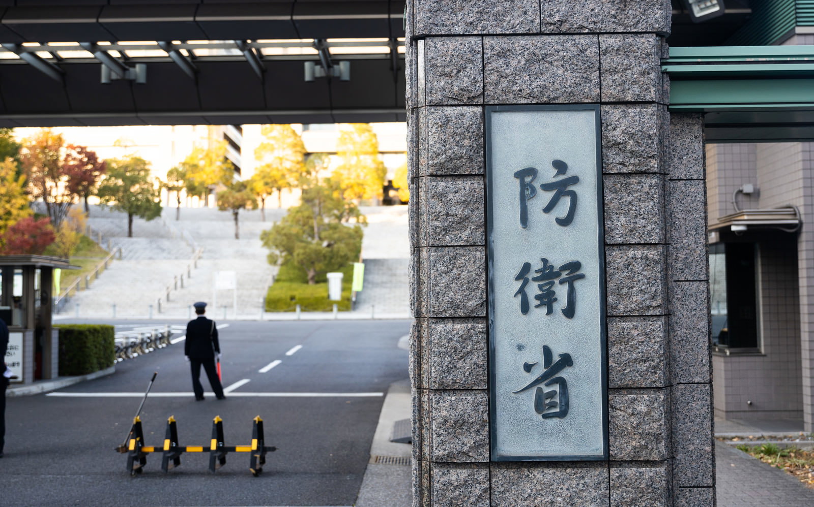 防衛省正門の石柱に刻まれた省庁看板と奥に見える正門建物