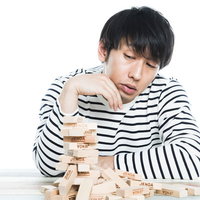 崩れたジェンガを前に残念そうに見つめるボーダー男子の写真