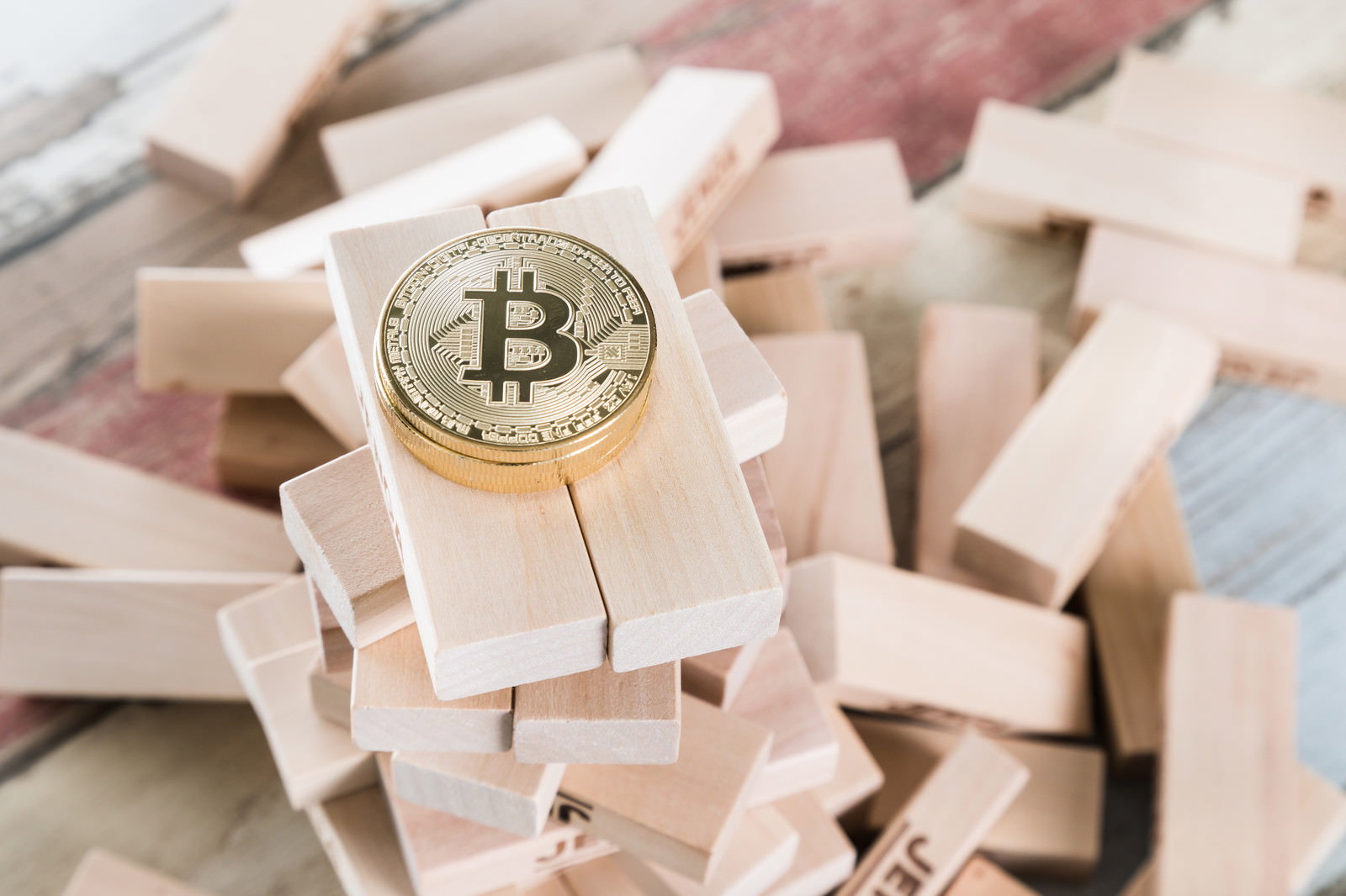 木製の積み木ブロックの上に金色のビットコインコインが置かれている