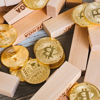 崩れたジェンガと金色のビットコイン：仮想通貨の投資リスクの写真