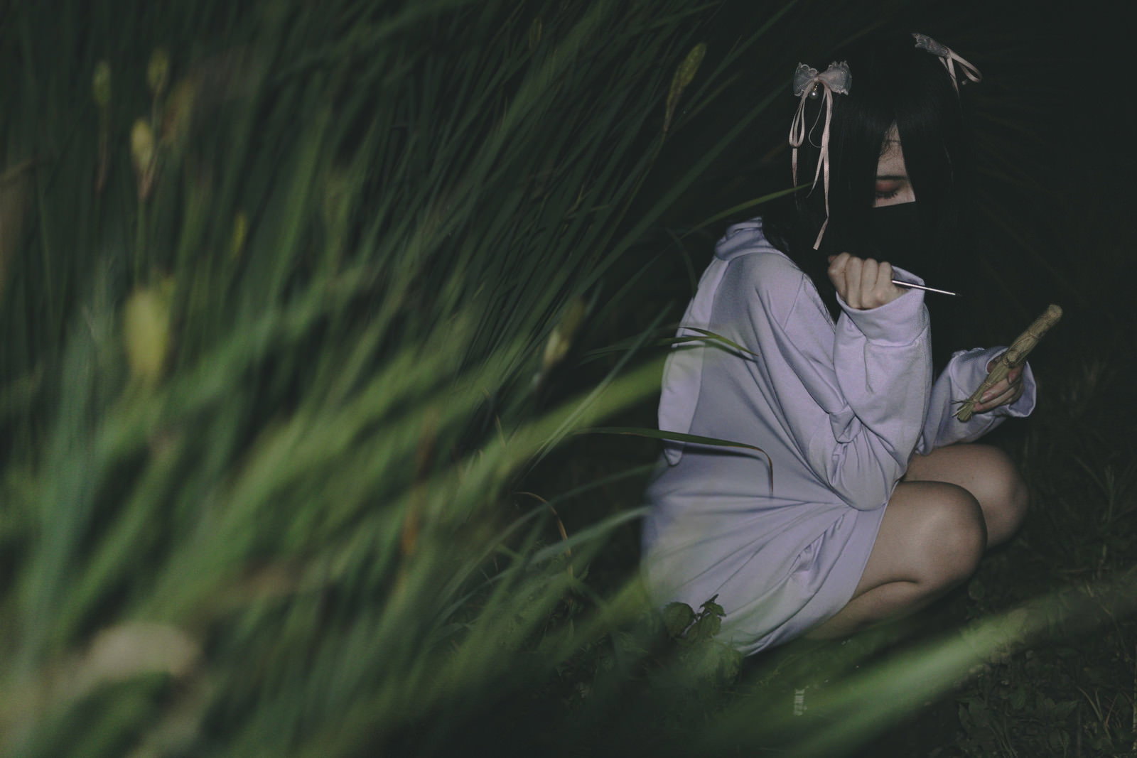 草むらで藁人形を抱えて座る白い衣装の女性［モデル：緋真煉］