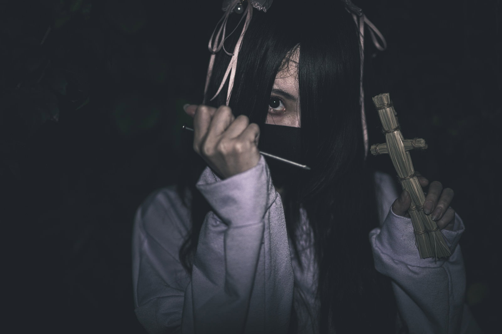 暗闇の中で藁人形と五寸釘を持つ黒髪の地雷系女子［モデル：緋真煉］