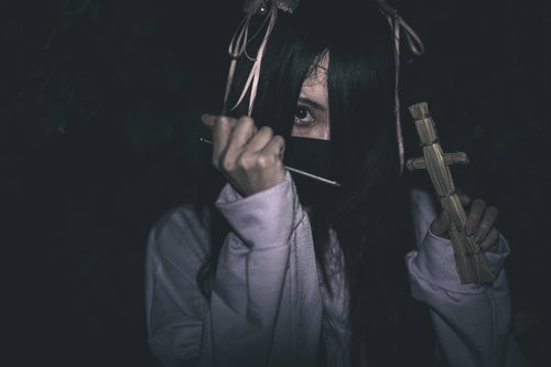 五寸釘を握る藁人形と地雷系女子の呪いの演出