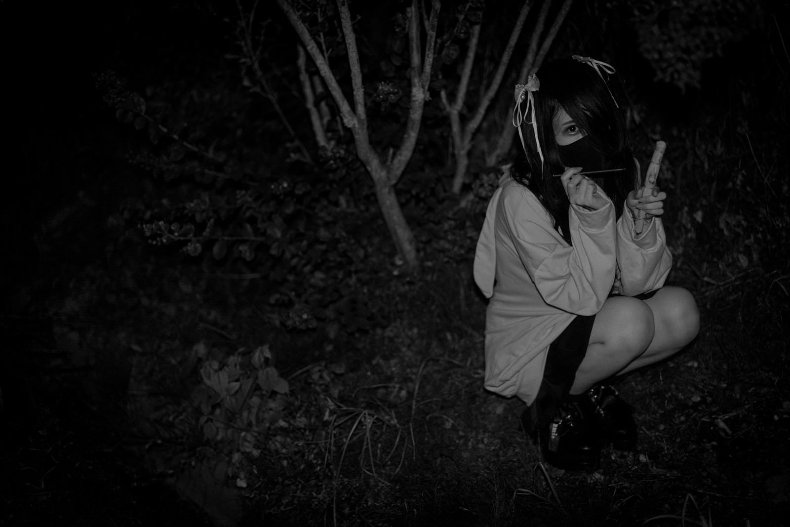 暗闇の中で藁人形を抱える地雷系女子の女性［モデル：緋真煉］