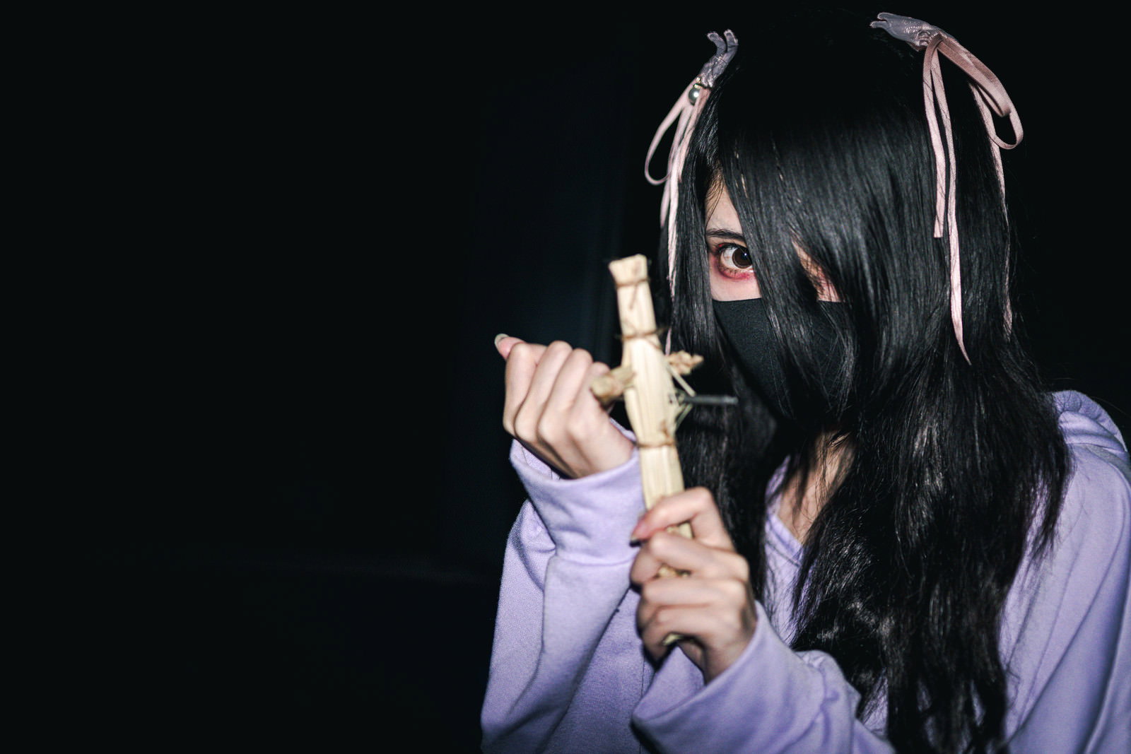 暗い背景で藁人形を手に持つ地雷系女子の人物写真［モデル：緋真煉］