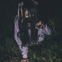 紫色の衣服を纏い暗い草地で這いつくばる地雷系女子の怨霊の写真