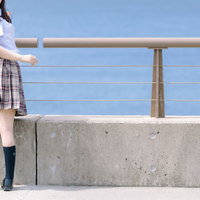 防波堤前で振り返る女子高生、海を背景に青春を表現の写真