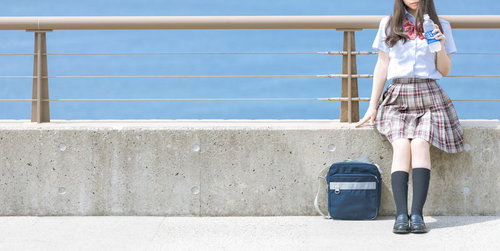 拝啓、暑い日が続いておりますがいかがお過ごしですか。海岸でペットボトルを手にした女子高生